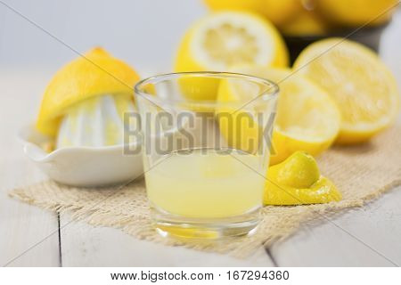 A glass of squeezed lemon juice and lemons around.