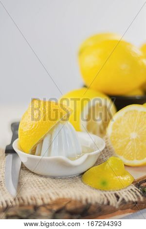 Juicer for lemon on a wooden plank and cut and whole lemons around.