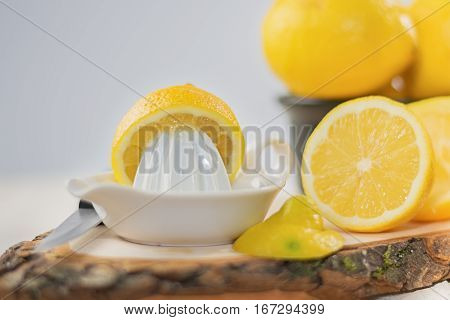Juicer for lemon on a wooden plank and cut and whole lemons around.