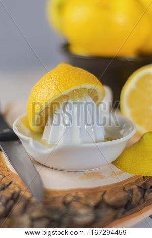 Juicer for lemon on a wooden plank and cut and whole lemons around.