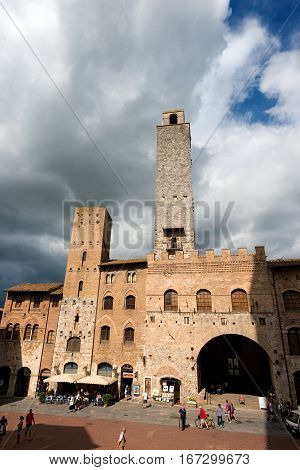 SAN GIMIGNANO ITALY - JULY 12 2014: Tourists visit the ancient and medieval Piazza del Duomo (Cathedral square). San Gimignano (UNESCO heritage) Siena Tuscany Italy