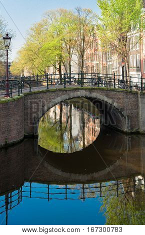 View of historical bridge over canal with mirror reflections in water, Amstardam, Netherlands