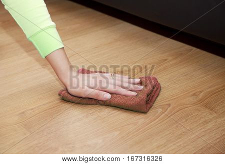 woman's hand cleaning the wooden floor with a brown floorcloth closeup