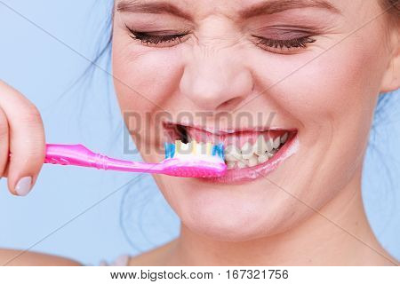 Woman brushing cleaning teeth. Girl with toothbrush. Oral hygiene. Blue background
