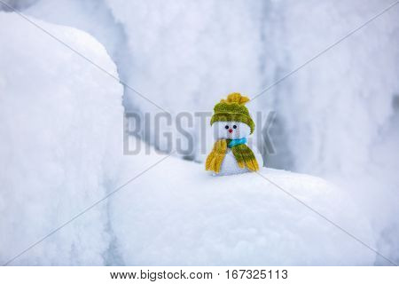 Incredible beautiful interesting white snow froze in strange textures forms and snowflakes and among all this beauty there is a little snowman in a hat and scarf.