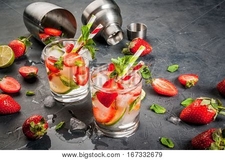 Summer refreshing mojito cocktail with strawberry mint and lime on a dark gray stone (concrete) table with shaker for whipping drinks copy space