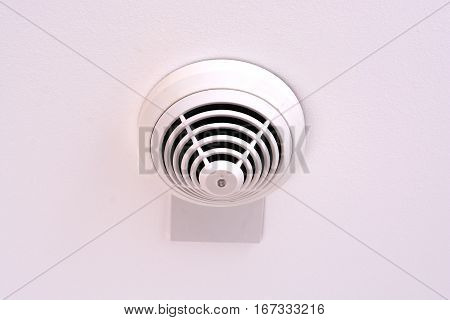 Modern smoke sensor installed on white ceiling