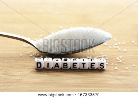 Plastic letter beads spelling "diabetes" and a spoon full of sugar