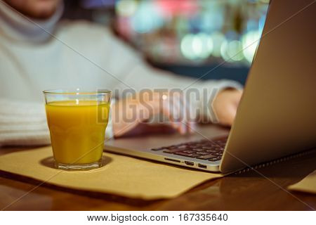 man drinks juse while working on laptop in cafe