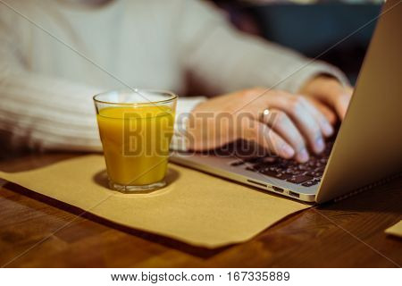 man drinks juse while working on laptop in cafe