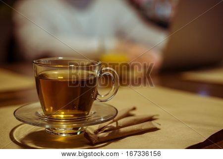 cup of tea on a table with working man on laptopn in background