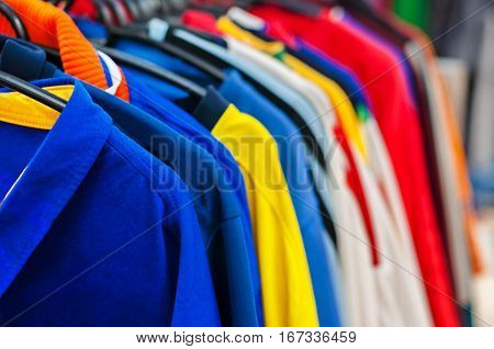 Lots of bright colorful clothes on hangers in shop.