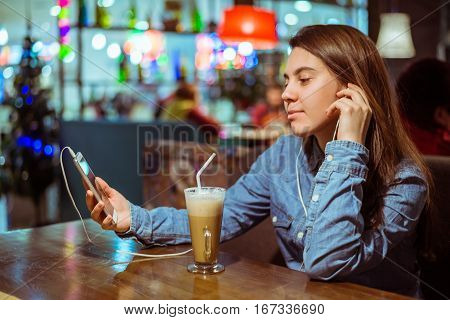 Music smartphone in female hand, on cafe interior background, injoy