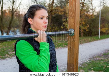 Young athlete effortlessly doing one-hand pullups. Outdoor fitness.