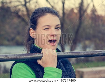 Young athlete effortlessly doing one-hand pullups. Outdoor fitness.