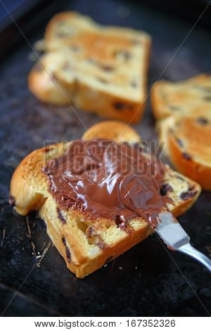 Slices of chocolate chip brioche one with chocolate hazelnut spread on an old metal cookie sheet