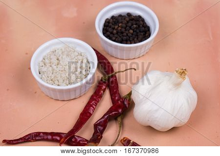 Gray Salt, Peppercorns, Dried Red Peppers And Garlic On Saltillo Tile