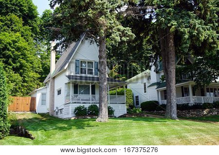A Victorian home with a wraparound porch and a very steep roof, under the bluff on Fourth Street in Harbor Springs, Michigan, during August.