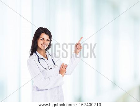 Young handsome friendly smiling and experienced female doctor shows his hand to the side for your advertising text or products in the field of medicine