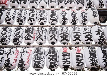 Japanese decorations with japanese inscriptions written inside a buddhist temple. The white colored round shaped designs looks beautifully arranged in a row.