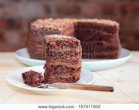 Piece of chocolate cake with frosting, cut cake on the back
