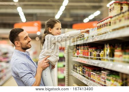 family, sale, shopping, consumerism and people concept - happy father with child buying food at grocery store