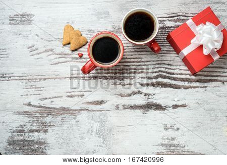 two red coffee cup, hearts cokies and gift box on wooden surface. Valentines day concept.