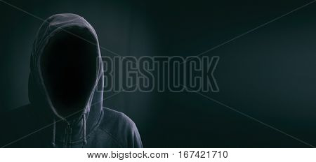 Hooded faceless man on a black background