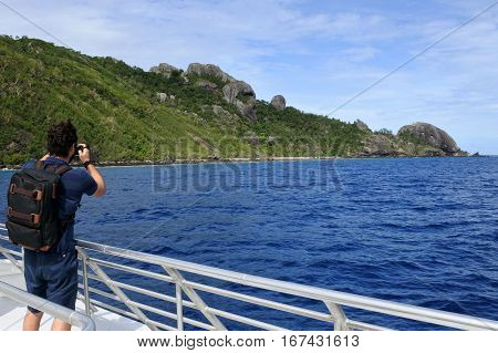 Travel photographer photographing the landscape of a tropical island in the Yasawa group in Fiji from a boat. Real people copy space