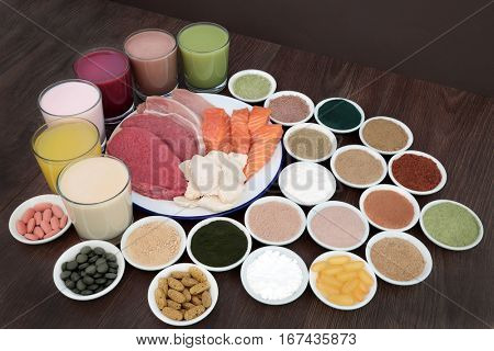 Health food and drinks for body builders with lean meat of steak, chicken and pork with salmon and dietary supplemment powders and vitamin pills on oak background.