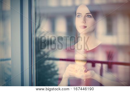 Beautiful Rednead Woman With Cup Of Coffee Or Cappuccino Near A Window Reflection