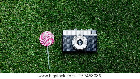 Vintage Camera And Lollipop Candy On Green Grass Background