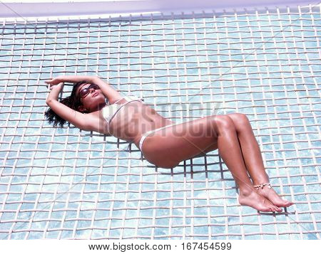 Lying down woman sunbathing on hamaca sailboat.