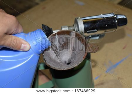 Pouring gasoline blowtorch through the a  funnel.