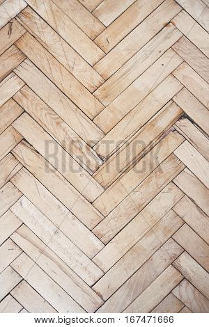 Top view on rich texture of vintage and distressed wooden parquet floor pattern made from many racks in herringbone shape, vertical image