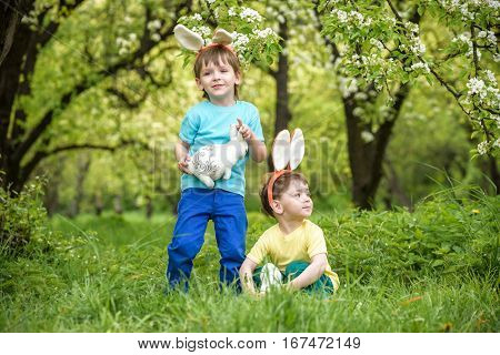 Two Little Kids Boys And Friends In Easter Bunny Ears During Traditional Egg Hunt In Spring Garden,
