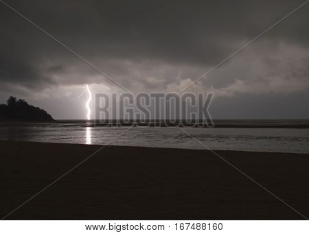 Incredibly sharp lightning with branches hitting the ocean with reflected light