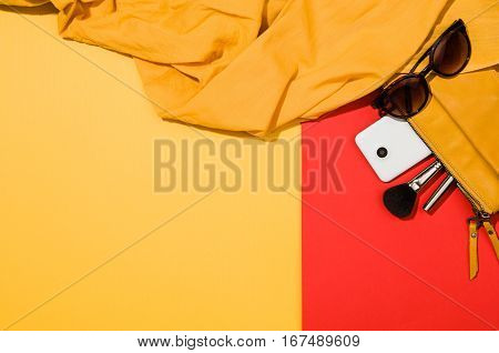 Woman's accessories flat lay on colorful background. Top view. Red and yellow pastel colors with copy space around products. Horizontal image or photograph.