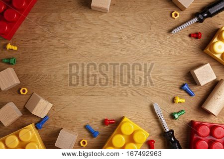 Kids toys background. Colorful toy tools, construction blocks and cubeson wooden table. Top view. Flat lay