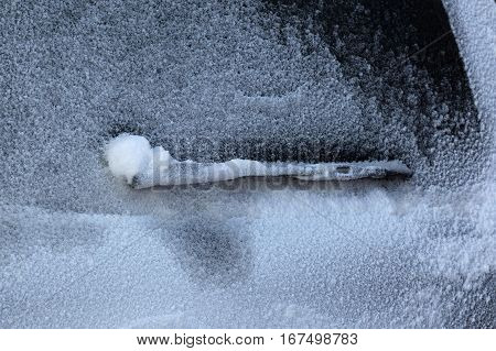 Snow. Windscreen wiper on a car covered with snow.