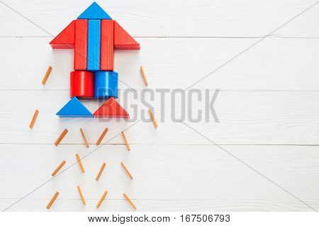 Abstract rocket from colored wooden blocks on a white wooden background with copy space. Business concept startup achievement success. Wooden puzzle in rocket shape discovery concept