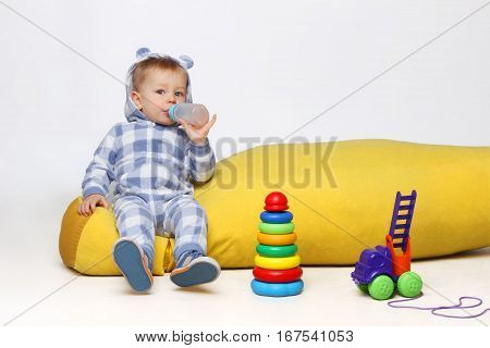 Shot of a little baby boy playing with some toys and drinking from a sippy cup.