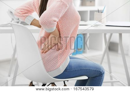 Beautiful young woman suffering from backache in office