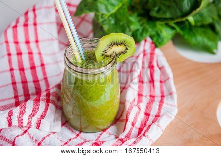 Homemade Healthy Green Smoothie With Spinach And Kiwi In A Jar Mug With A Straws On A Checkered Napk