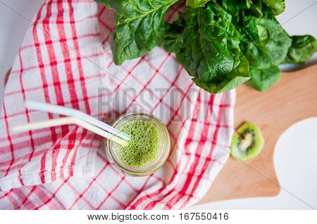 Top View Homemade Healthy Green Smoothie With Spinach And Kiwi In A Jar Mug With A Straws On A Check