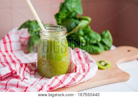 Homemade Healthy Green Smoothie With Spinach And Kiwi In A Jar Mug With A Straws On A Checkered Napk