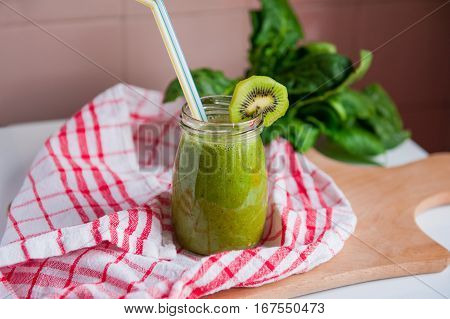 Homemade Healthy Green Smoothie With Spinach And Kiwi In A Jar Mug With A Straws On A Checkered Napk