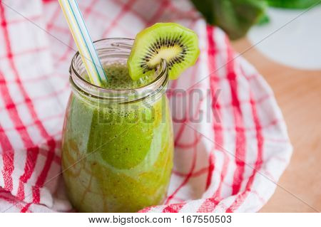 Homemade Healthy Green Smoothie With Spinach And Kiwi In A Jar Mug With A Straws On A Checkered Napk