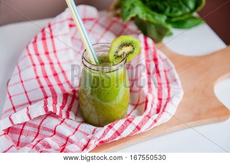 Homemade Healthy Green Smoothie With Spinach And Kiwi In A Jar Mug With A Straws On A Checkered Napk