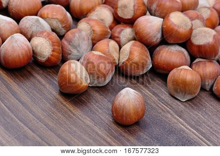 Many hazelnuts on wooden table close up